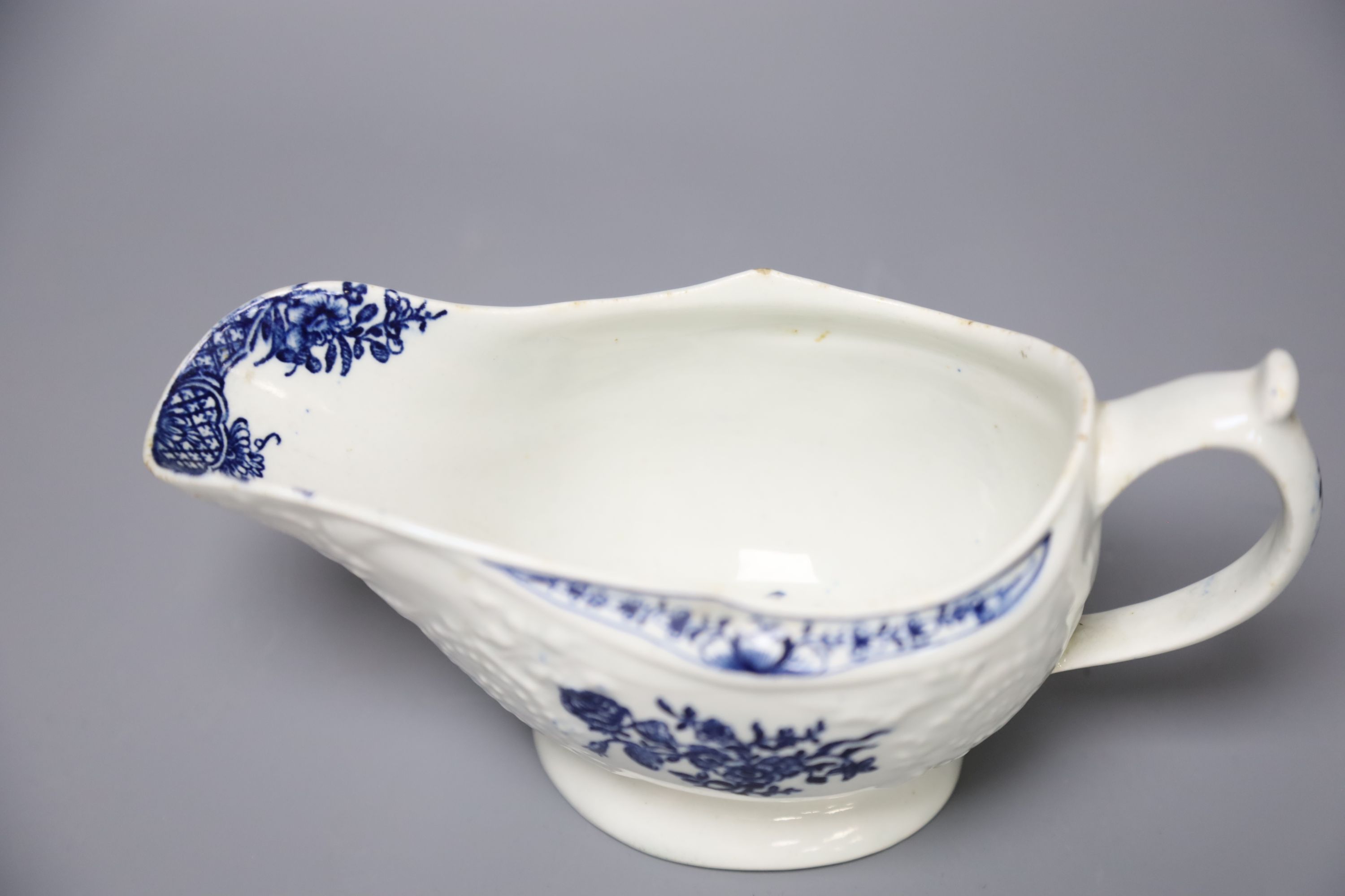 An 18th century Lowestoft floral moulded sauceboat flower in blue to each side and inside base, length 20cm